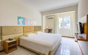 a bedroom with a large white bed and a tv at GoldMen Business Joinville in Joinville +45 photos