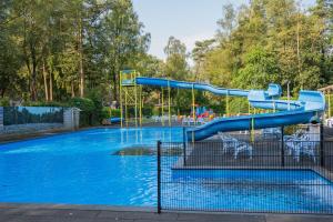 ein Wasserpark mit einer blauen Rutsche darin in der Unterkunft Forest Finest, luxe chalet met HOT TUB mooie overkapping en prachtige tuin met veel privacy in Hoenderloo
