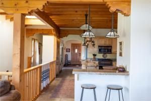 a kitchen with wooden ceilings and a kitchen island with stools at Side-by-side Adobes, 9 Mi To Taos Ski Valley in Valdez