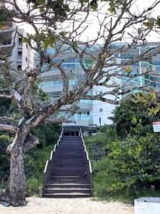 a staircase leading up to a building with a tree at Bacutia, prédio frente ao mar! in Guarapari