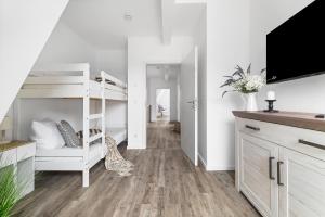 a white bedroom with a bunk bed and a tv at Ferienhaus Donnerkeil Fehmarn in Fehmarn