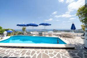 a swimming pool with blue umbrellas and chairs at Relais Bijoux Ischia in Ischia