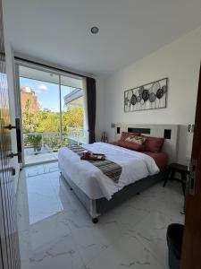 une chambre avec un grand lit et une grande fenêtre dans l'établissement Villa Bella Jimbaran, à Jimbaran