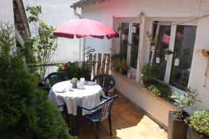 una mesa y sillas con una sombrilla rosa en el balcón en Ferienwohnung Röck, en Hornberg