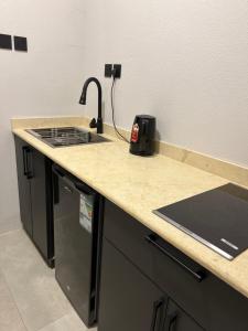 a kitchen counter with a sink and a stove at شقق السابعة السكنية in Buraydah