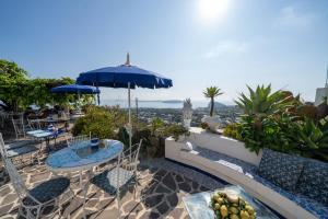 a patio with tables and chairs and an umbrella at Relais Bijoux Ischia in Ischia