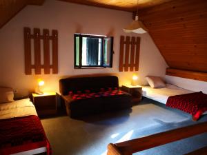 Ski Cottage في Semič: غرفة بها سريرين وأريكة ومصباحين