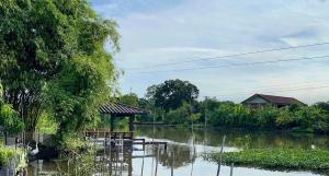 a view of a river with a table and a hut at Croc Camp in Lat Krabang +2 photos