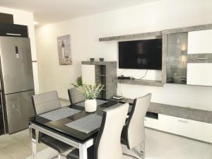 a dining room with a black table and white chairs at Apartamento en Victoria Park Playa San Juan in Playa de San Juan