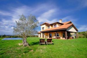 a house with two chairs in front of a tree at La Casa de Orviz in Siero