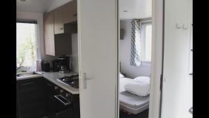 eine kleine Küche mit einem Waschbecken und einem Bett in der Unterkunft Bungalow Camping 4 à 8 personnes in Les Mathes