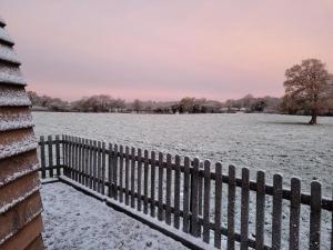 a fence covered in snow next to a field at Fir Tree Farm by Wigwam Holidays in Whitchurch
