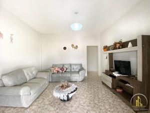 a living room with a couch and a tv at Casa da Lu, em Santa Monica in Guarapari