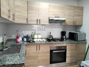 una cucina con armadi in legno, lavandino e forno a microonde di Résidence les deux palmiers Temara Rabat a Temara