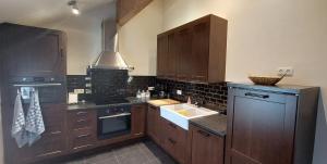 a large kitchen with wooden cabinets and a sink at Les Champs aux Boules Ambiance très cosy in Herbeumont