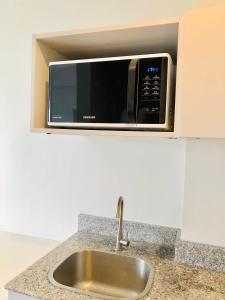 a microwave oven above a sink in a kitchen at Cozy and Sunny Apartment near to Mactan Cebu International Airport - Amani Grand Resort & Residences in Pusok