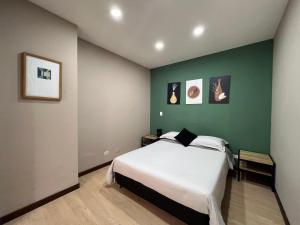a bedroom with a bed and a green wall at Económico alojamiento en Medellín por días - A102 By Roots Rentals in Medellín