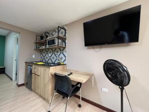 a kitchen with a desk and a television on a wall at Económico alojamiento en Medellín por días - A102 By Roots Rentals in Medellín