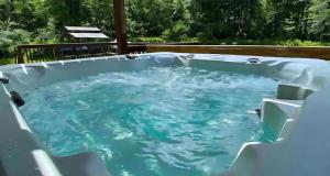 wanna z hydromasażem na podwórku z błękitną wodą w obiekcie Peaceful Pocono Home with Hot Tub, gym, & office w mieście Long Pond