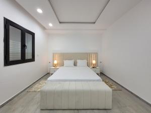 a white bedroom with a large bed and two tables at Villa Yara in Djerba +77 photos