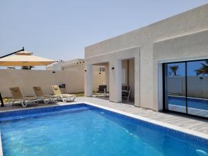 a swimming pool in front of a house at Villa Yara in Djerba