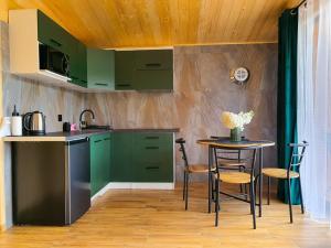 a kitchen with green cabinets and a small table at Roztoczański Domek nad Stawem z jacuzzi in Nowiny