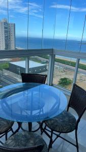 a glass table and chairs with a view of the ocean at Apartamento Beira Mar em Praia de Itaparica - Vila Velha- ES in Itaparica