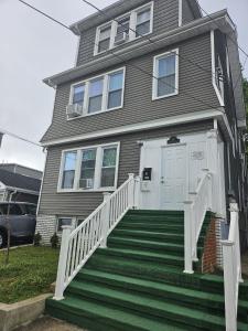a gray house with a white door and stairs at TKC Homes in Irvington