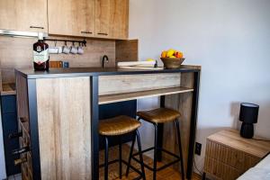 a kitchen with a bar with stools and a bottle of wine at Studio apartman Valpovo in Valpovo