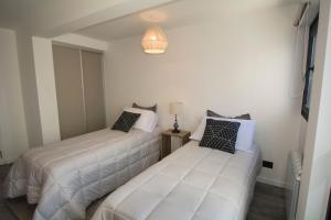 two beds in a room with white walls at Espacio nuevo, tranquilo y céntrico en Bariloche in San Carlos de Bariloche