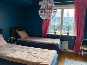 a blue room with two beds and a chandelier at Strandvillan Gnesta in Gnesta +15 photos