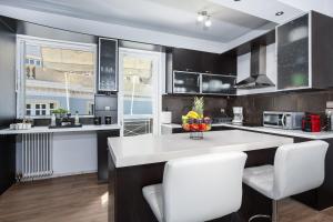 a kitchen with black and white cabinets and white chairs at Villa Costa Luca in Vouliagmeni in Athens