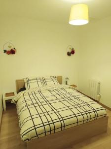 Un dormitorio con una cama con una manta blanca y negra. en Le petit cocon, en Pont-lʼÉvêque