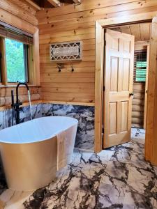 a tub in a bathroom with a wooden wall at Camp Cozy in Pigeon Forge