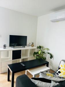 Agréable Studio proche Aéroport de Bordeaux في BOD: غرفة معيشة مع طاولة قهوة سوداء وتلفزيون +صورتان