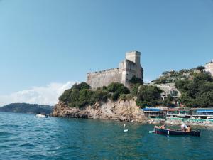 een boot in het water voor een kasteel bij Casa Shanty in La Spezia