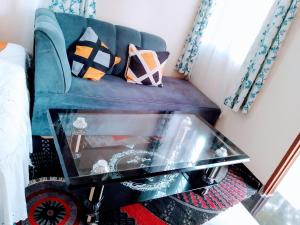 a living room with a blue couch and a glass coffee table at KANAPRIME-Studio Apartment in Shanzu
