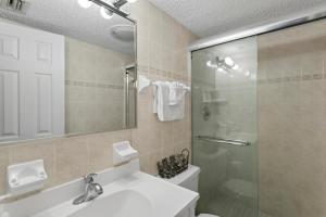 a bathroom with a shower and a sink and a toilet at Fifty Gulfside Condominiums in Clearwater Beach +14 photos