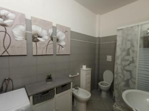 a bathroom with a toilet and some paintings on the wall at IL NIDO - Intero Appartamento Forum & Humanitas in Rozzano +6 photos