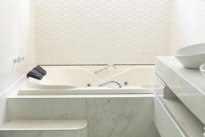 a white bathroom with a tub and a sink at Casa Jardim - Praia do Bessa por Carpediem in João Pessoa