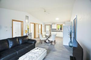 a living room with a black leather couch and a kitchen at Tucked Away Walk to Beach Pet Friendly Relax in Rothesay
