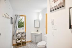 Un baño con inodoro, lavabo y espejo. en Tucked Away Walk to Beach Pet Friendly Relax, en Rothesay