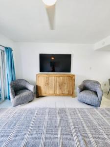 a living room with two chairs and a flat screen tv at 7Mile Beachfront Apartment in George Town