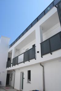 an external view of a white building with balconies at Le Casette di Eolo in Roca Vecchia
