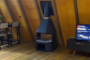 a stove in the middle of a room with a tv at Chalé dos Alpes 1 hidromassagem e Lareira in Santo Amaro da Imperatriz