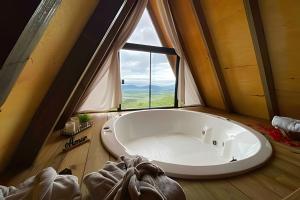 a large tub in a room with a large window at Chalé dos Alpes 1 hidromassagem e Lareira in Santo Amaro da Imperatriz +29 photos