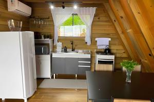 a kitchen with a white refrigerator and a sink at Chalé dos Alpes 1 hidromassagem e Lareira in Santo Amaro da Imperatriz