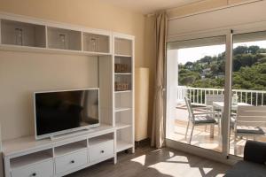 Una sala de estar con televisión y balcón. en SeaHomes Vacations - Seafront Apt Fenals with PKG, en Lloret de Mar