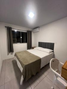Un dormitorio con una cama y un escritorio y una ventana. en Suíte com BWC PRIVATIVO Com AR Ao Lado da Vila Germânica Oktoberfest, en Blumenau