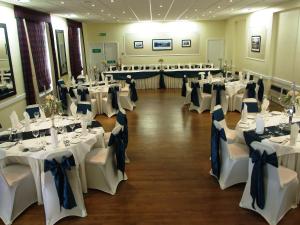 a banquet hall with white tables and chairs with blue bows at The Royal Hotel Tain in Tain